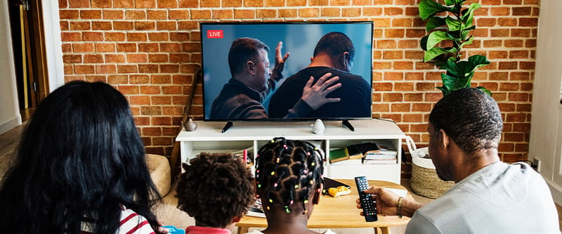 Family on couch watching church online on home TV