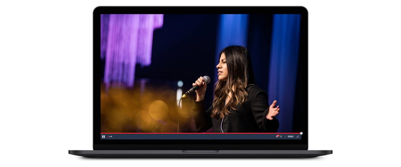 Pastor speaking and praying into microphone on church live stream playing on a laptop