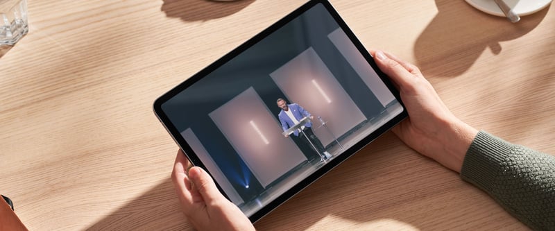 Person watching a church live stream of a pastor speaking on a tablet