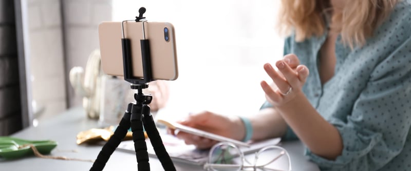 Person streaming with an iPhone attached to a desktop tripod