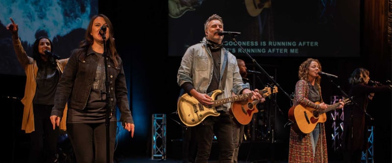 Worship band sings and plays guitar on stage