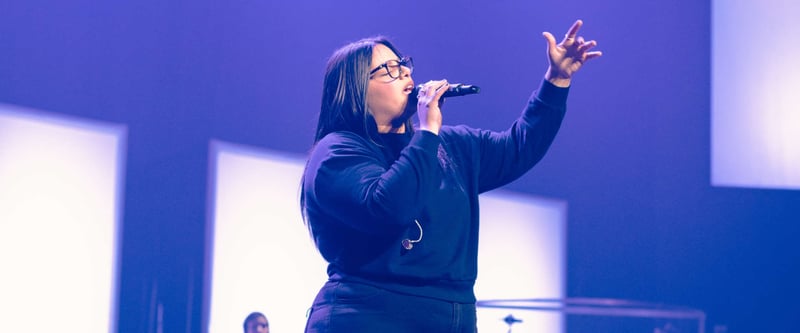 Worship team member sings into a microphone during a Sunday service