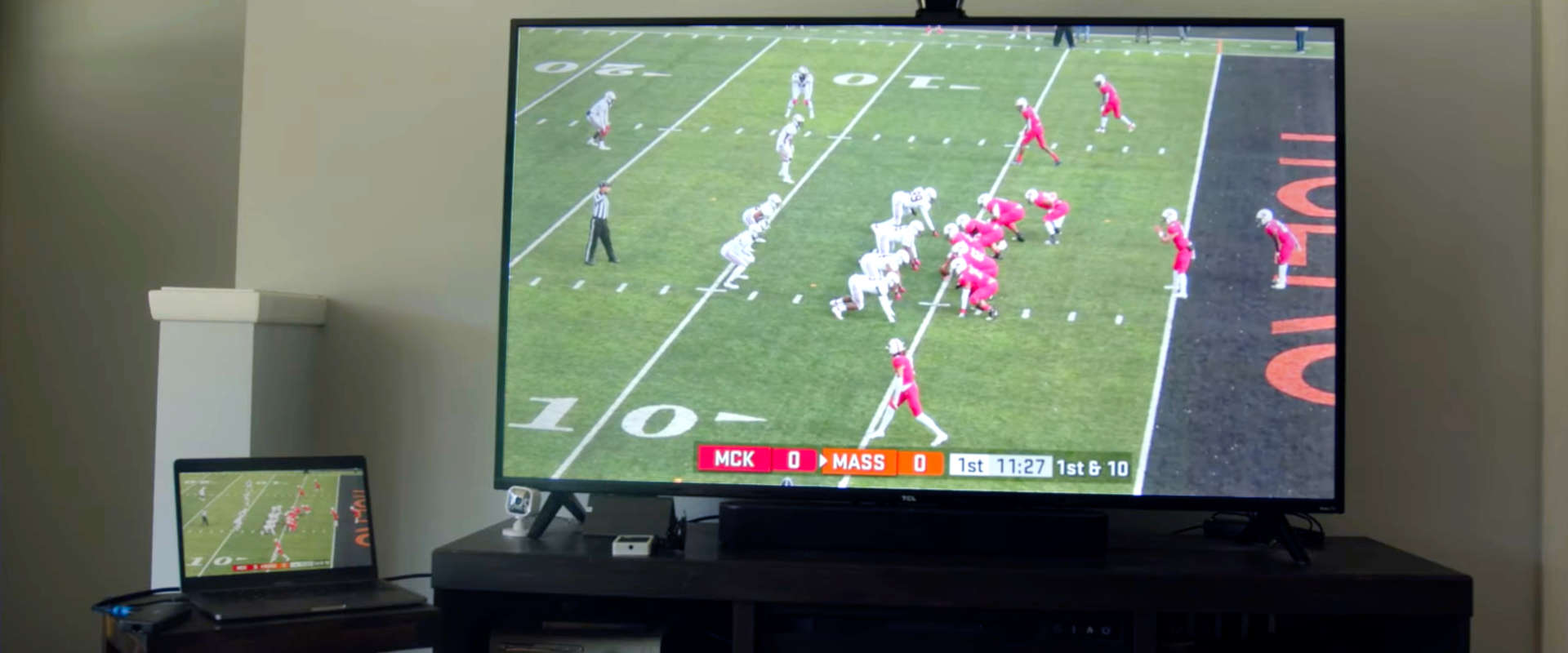 Laptop connected to smart TV with HDMI cable live streaming a football game
