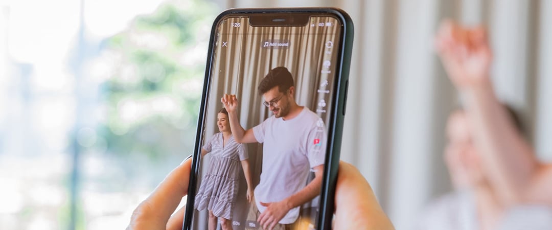 Two people filming themselves dancing on an iPhone for TikTok, Instagram, and YouTube