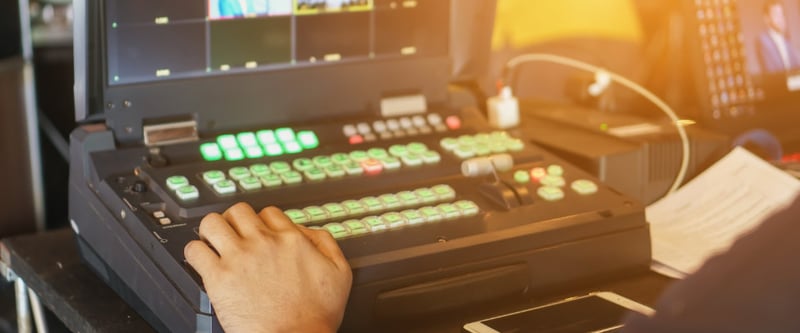 Video producer monitoring a multi-cam live stream with a switcher showing multi-view