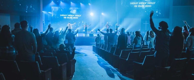 Church service with crowd standing up and raising arms