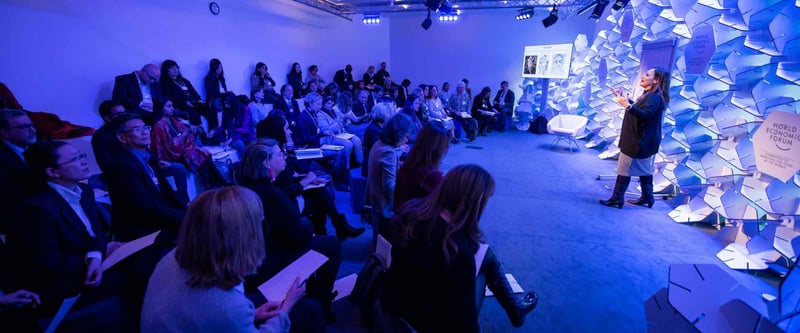 Shot of a crowd sitting and reacting to a speaker giving a presentation