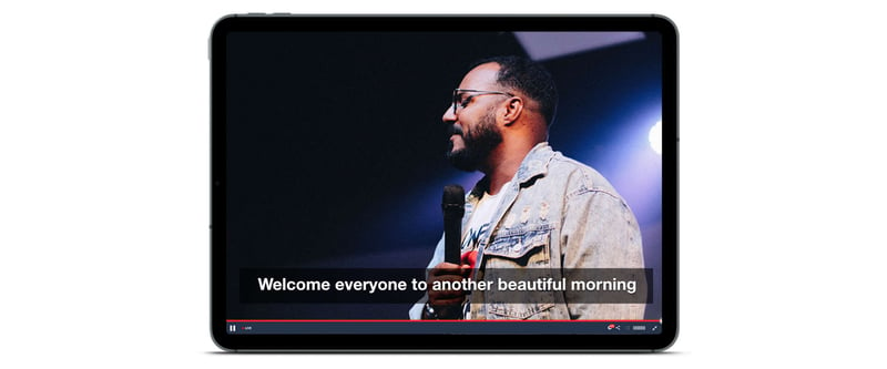 Live stream playing on an iPad with presenter speaking and closed captions
