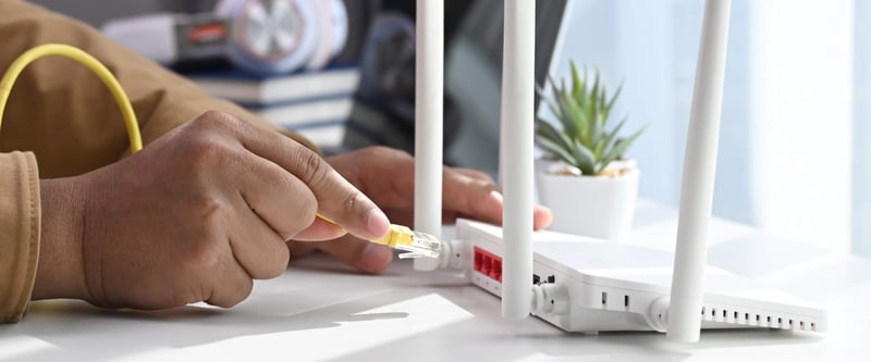 Person plugging ethernet cable into a router