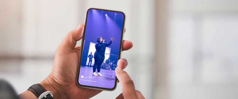 Hand holding phone showing live stream of church worship service on YouTube Shorts