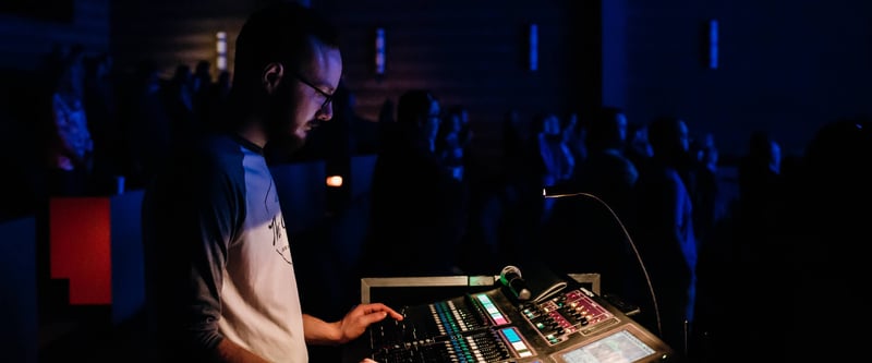 Church media producer running sound and video at church production booth