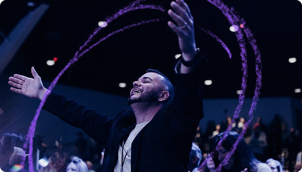 Man smiling with arms raised in church service