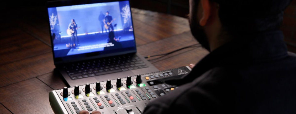 Image of someone watching a live stream on a laptop while mixing the audio on the mixer in front of them
