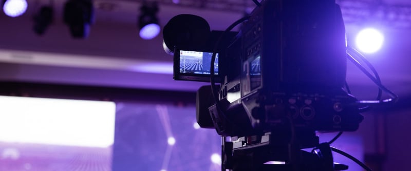 Camera on stand pointed towards stage with dramatic lighting