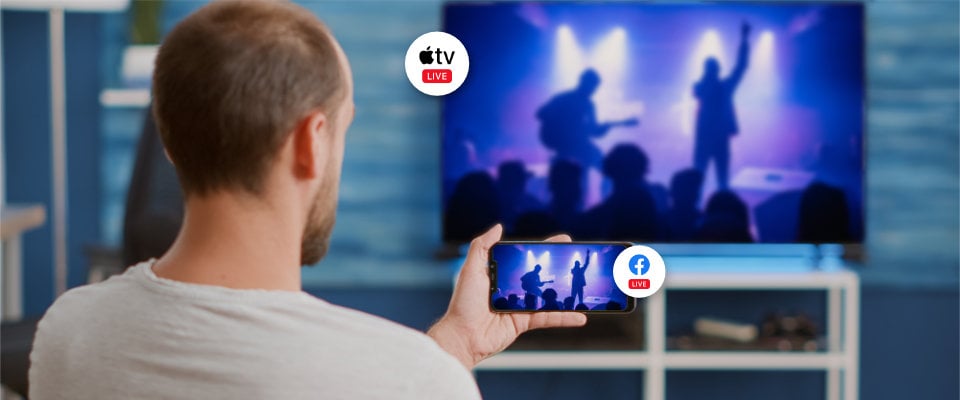Man watching a multistreamed concert on Facebook live and his TV at the same time
