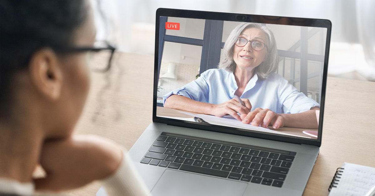 Woman watches presenter on laptop screen during live virtual conference