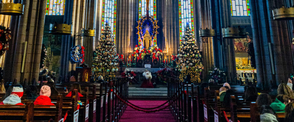 Church cathedral and sanctuary decorated with Christmas trees and members in pews