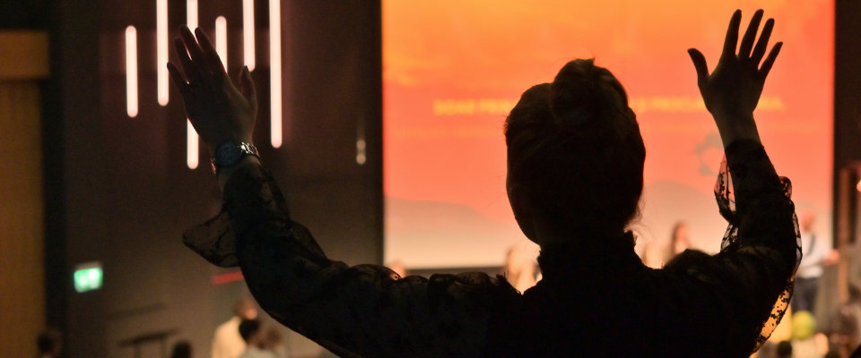 Woman raising hands in a church worship service on Easter