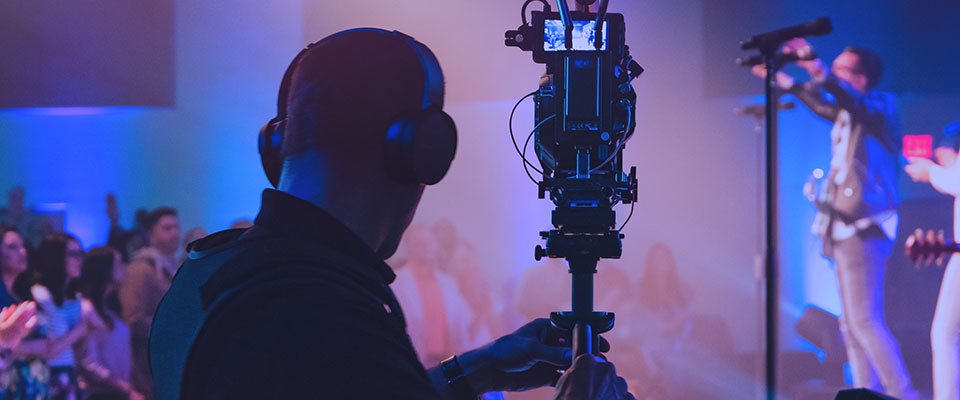 silhouette of a man operating a video camera during a church performance