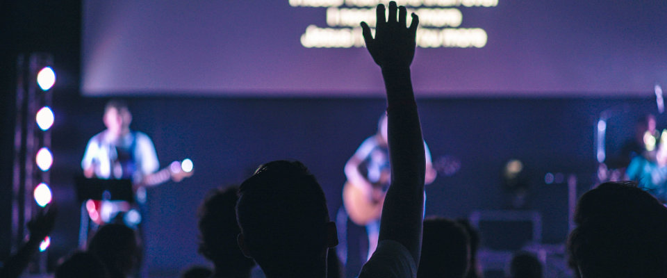Person raising hand in audience of worship service