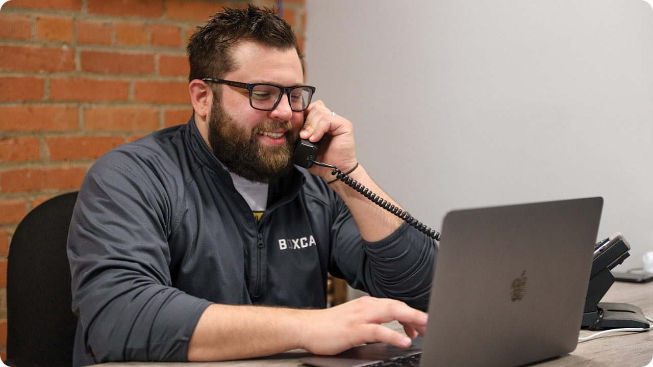 Photo of sales person talking on the phone while working on a laptop
