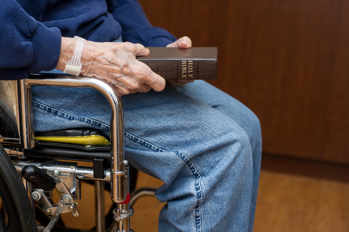 Senior man in wheelchair holding a Bible