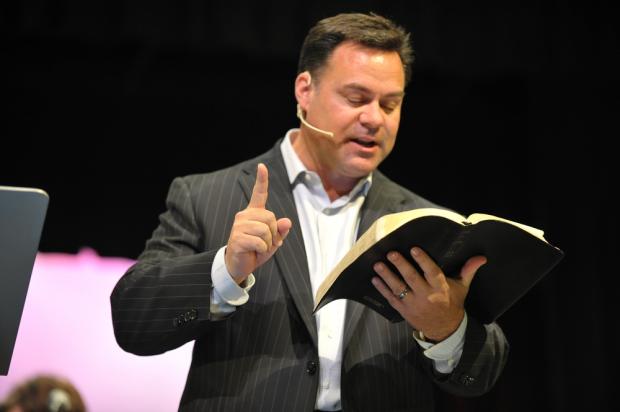 Pastor reads from Bible on stage