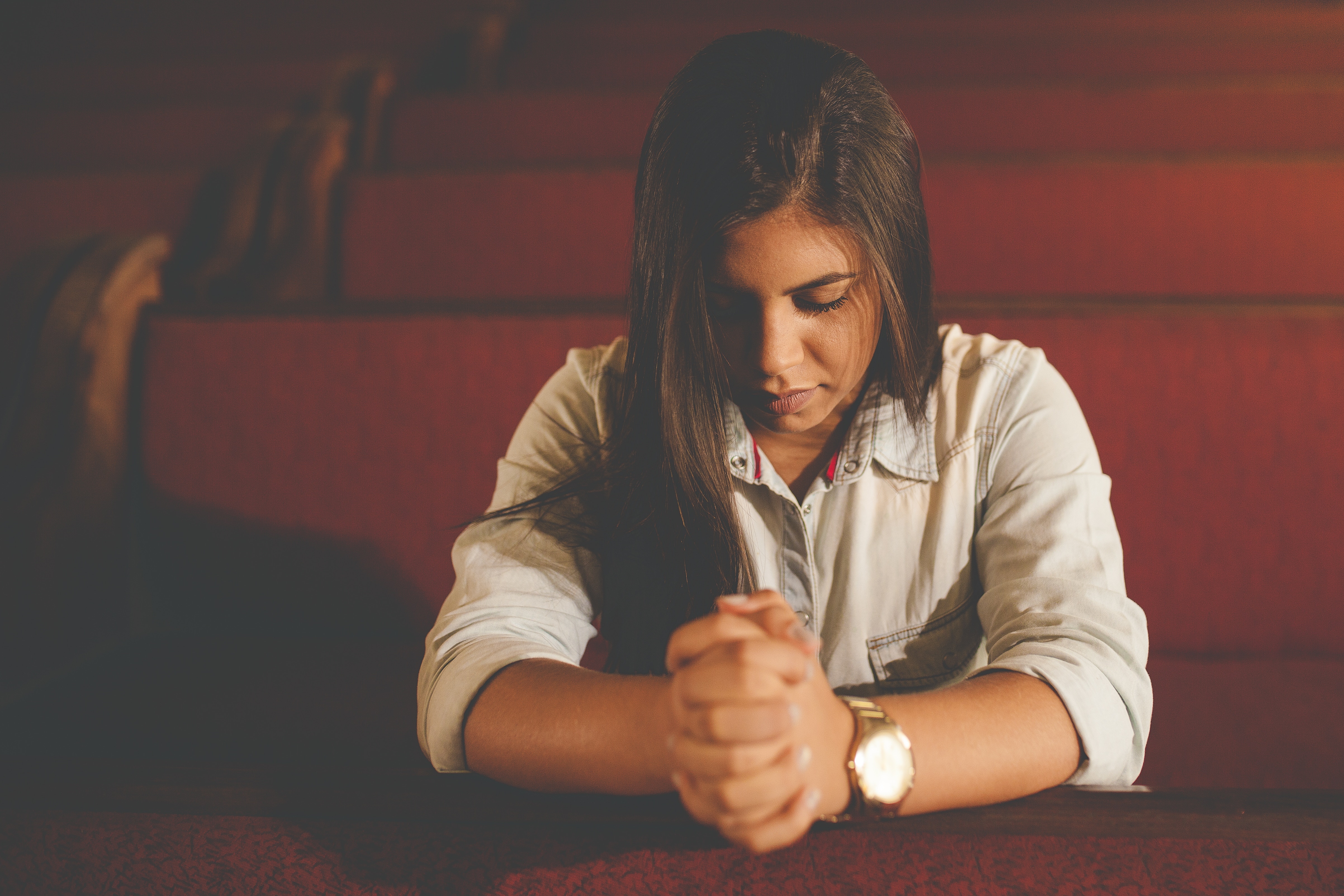 Young woman praying in a church pew